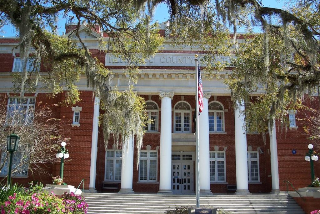 Red-brick Hernando County Courthouse in Brooksville, with white columns under Spanish moss