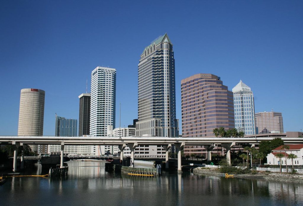 Downtown Tampa skyline under a clear blue sky, with the high-rises reflected in the water below