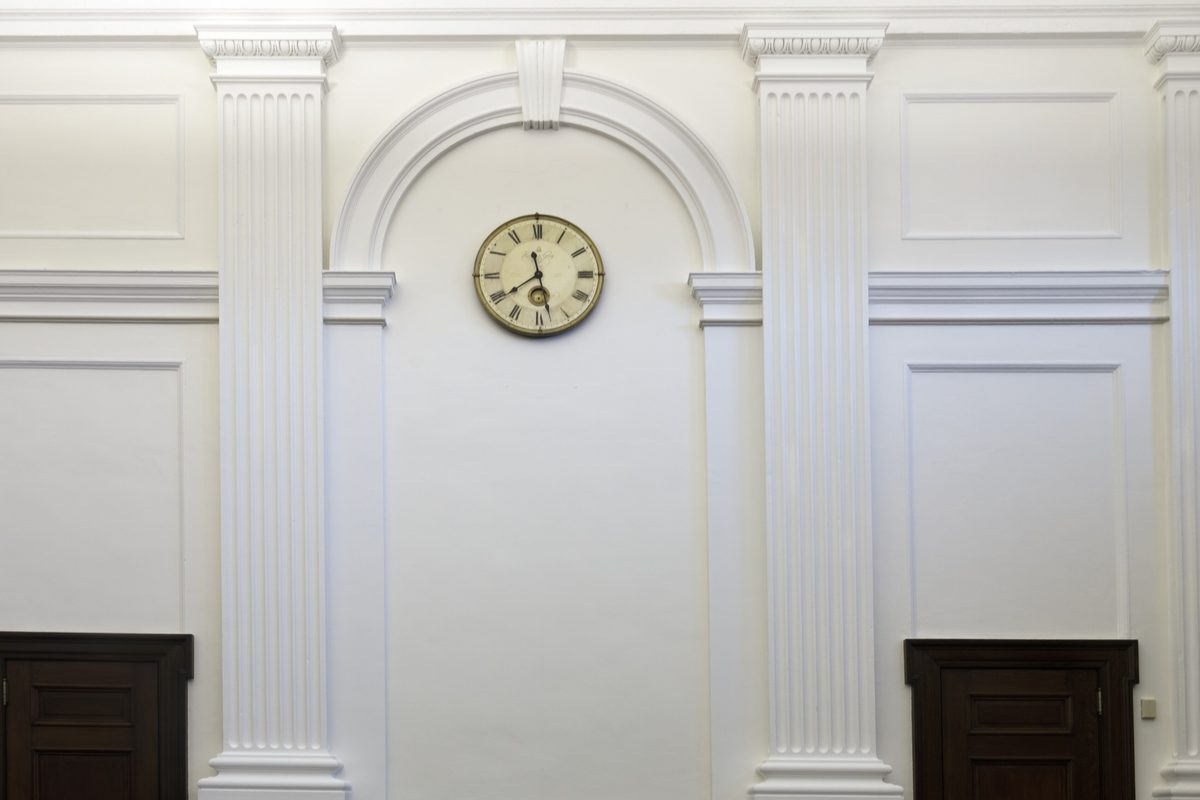 Violation of probation Tampa: a round clock on a white paneled courtroom wall between columns above dark wooden doors